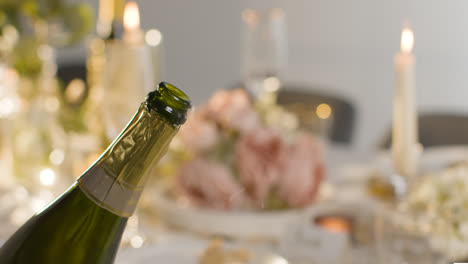 Close-Up-Of-Person-Opening-Bottle-Of-Champagne-At-Table-Set-For-Meal-At-Wedding-Reception